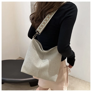 Détail du sac cabas tissé minimaliste avec large bandoulière brodée et finitions dorées