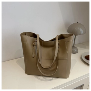 Gros plan sur la texture du sac cabas kaki et les coutures sur une table blanche
