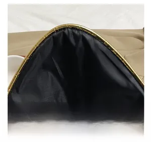 Detail of minimalist envelope clutch featuring gold metallic trim and premium black lining