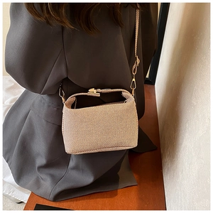 Detail showing the vintage striped fabric texture and gold metal clasp on a crossbody bag