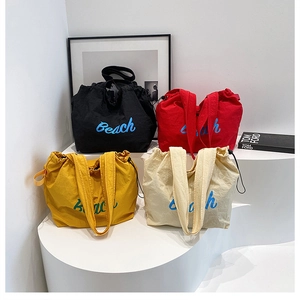 Detailed display of tote bags in black, red, yellow, and beige with Beach lettering