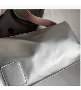 Detail of silver metallic pillow bag with square stitching and pink shoulder strap
