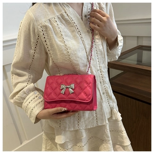 Détail du sac matelassé rose vif avec nœud argenté et bandoulière en chaîne élégante