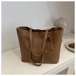 Grand sac cabas marron avec surpiqûres blanches contrastées dans un décor moderne