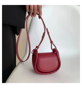 Detail of burgundy retro semi-circular crossbody bag with matte leather and gold buckle