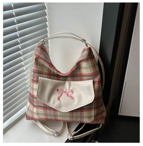 Detail of pink and green plaid tote bag featuring a front pocket and bow embroidery