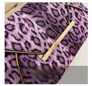 Detail of purple leopard print clutch bag featuring a sleek gold metal bar closure