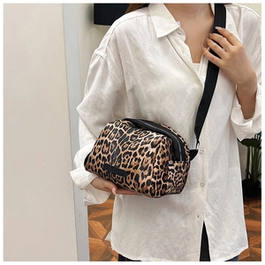 Detail view of leopard print crossbody bag with black wide strap worn by a model