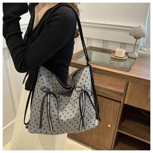Detail der grauen Hobo-Tasche mit schwarzen Herz-Prints und dekorativen Reißverschlusstaschen