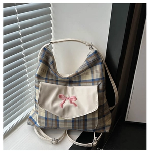 Detail of blue plaid tote bag with cream pocket and pink bow embroidery decoration