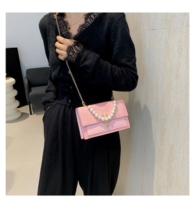 Détail du sac bandoulière rose avec poignée en perles et chaîne dorée sur mannequin