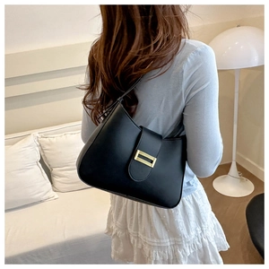 Detail of black faux leather baguette bag featuring a gold rectangular buckle closure