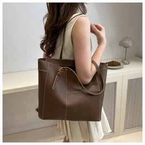 Brown tote bag with contrast white stitching detail shown on shoulder for daily commute