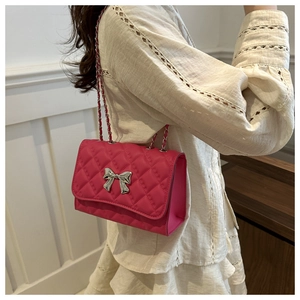 Detail of rose red quilted shoulder bag with silver bow and metal chain strap