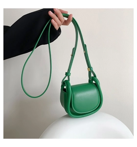 Detailed close-up of a bright green mini crossbody bag with a sleek U-shaped edge design