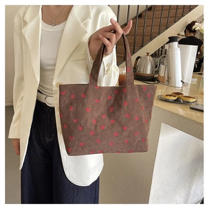 Détail d'un sac cabas en velours côtelé marron avec motifs fraises dans un café