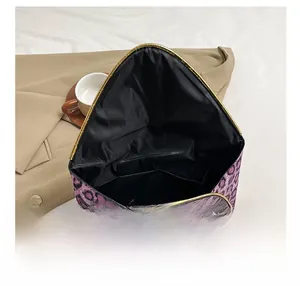 Interior detail of leopard print clutch showing open main compartment and inner pockets