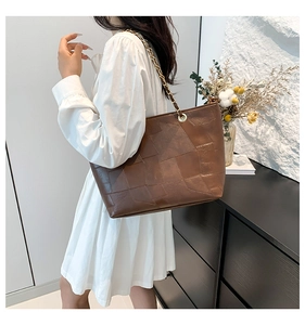 Detail of dark brown tote bag with vintage rectangular pattern and metal chain strap
