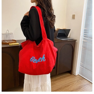 Close-up of a large red canvas tote bag with blue Beach embroidery for daily commuting