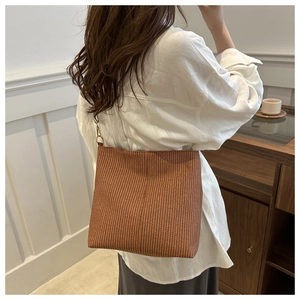 Brown woven bucket bag for women featuring a wide shoulder strap in a stylish casual design
