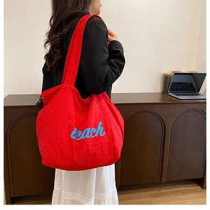 Close-up of a large red tote bag with blue Beach embroidery for casual beach outings