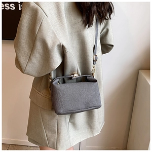 Close-up of a striped tote bag with gold hardware worn with a grey suit for a chic look