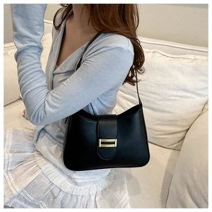 Close-up of black leather shoulder bag featuring a sleek gold rectangular buckle detail
