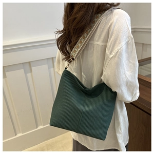 Detail of green pleated tote bag featuring a colorful ethnic jacquard shoulder strap