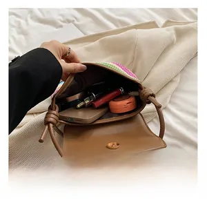 Detail show of the woven straw crossbody bag interior with phone and cosmetics storage