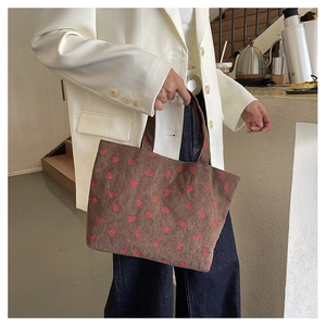 Detail showing brown corduroy tote bag texture with red strawberry print for daily use