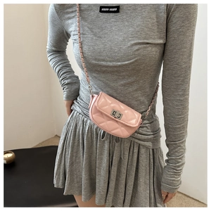 Detail of pink quilted leather crossbody bag with metal twist lock and chain strap