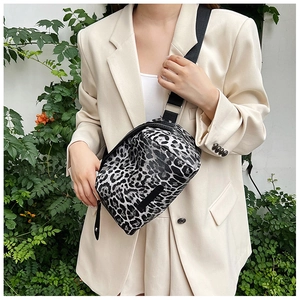Close-up of leopard print canvas chest bag with black strap worn by model