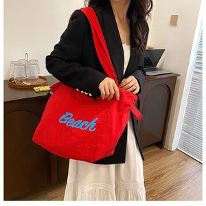 Detail of red nylon tote bag with blue Beach embroidery and wide shoulder strap