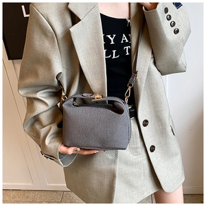 Detailed view of the gray textured bucket bag showing the golden twist lock and weave pattern