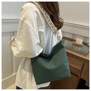 Détail du sac cabas vert foncé texturé avec une bandoulière à motifs géométriques rétro