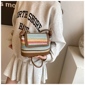 Detail of colorful woven straw crossbody bag with brown faux leather trim and strap