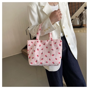 Sac cabas en velours côtelé rose avec motif fraise porté par un mannequin chic
