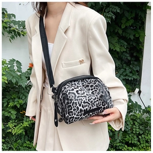 Detail of animal print shell bag with black strap worn over a beige blazer outfit