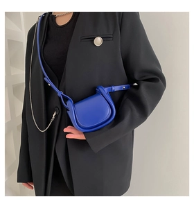 Minimalist blue leather saddle bag worn as a chest bag over a stylish black blazer