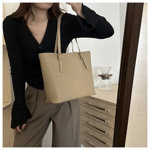 Detail view of khaki tote bag with white stitching shown in a home lifestyle setting