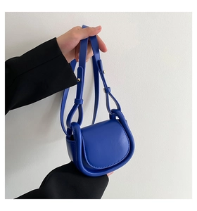 Detail of a mini vibrant blue saddle bag with adjustable leather strap and golden buckle
