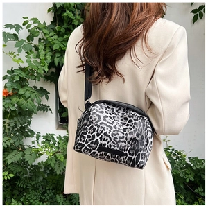 Close-up of leopard print shell crossbody bag on a model against a green leaf wall