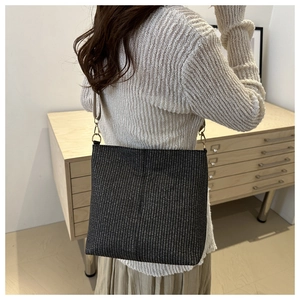 Détail du sac à bandoulière tissé avec sangle fine et finitions métalliques dorées