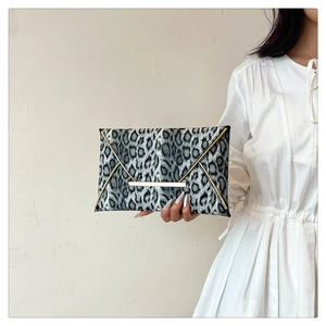Detail of leopard print envelope clutch featuring gold metallic trim and snap closure