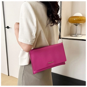 Close-up of magenta envelope clutch with gold metal bar and delicate chain strap