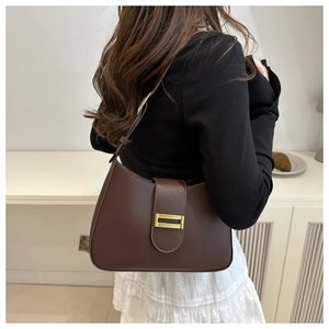 Detail of a brown leather underarm bag with a stylish gold metallic buckle on a shoulder strap