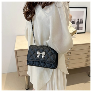 Détail du sac à bandoulière matelassé noir avec nœud argenté et chaîne métal