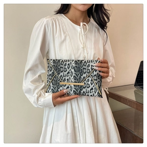 Detail of grey leopard print cotton clutch with elegant gold metal trim and buckle