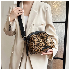 Close-up of leopard print canvas crossbody bag with wide black strap and metal buckle