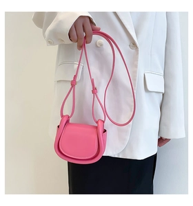 Pink leather mini crossbody saddle bag styled with white blazer on fashion model